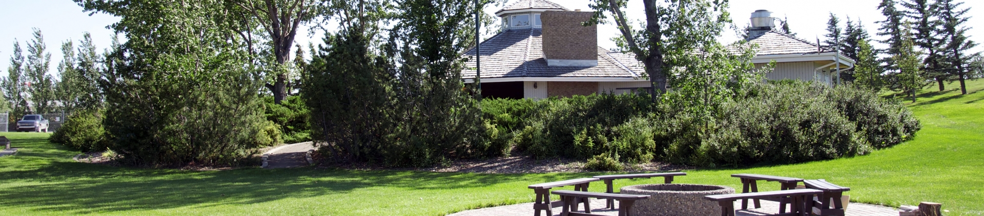 Kin Picnic Shelter with picnic tables and green grass in foreground.